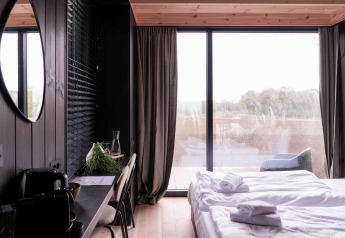 Moderne tiny house Nokken NKN-18 Cabin med stort vindue, udsigt til natur, seng og arbejdsplads, Wilsumer Berge.