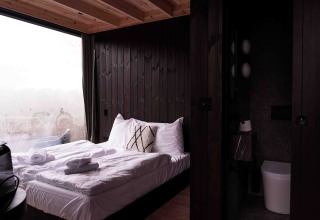 Interior de la Nokken NKN-18 Cabin en Wilsumer Berge, con acogedora cama y baño moderno abierto.