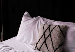 Cama con almohadas blancas y cojín decorativo en la Nokken NKN-18 Cabin en Wilsumer Berge, Alemania.