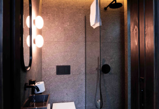 Baño moderno en la Nokken NKN-18 Cabin en Wilsumer Berge, Alemania, con ducha y espejos iluminados.