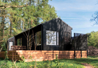 Koya Tiny Cabin, zwarte houten lodge met terras, gelegen in het bos van Wilsumer Berge, Duitsland.