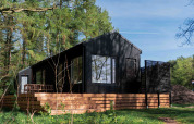 Zwarte Koya Tiny Cabin met houten terras, omringd door bos in Wilsumer Berge, Duitsland.
