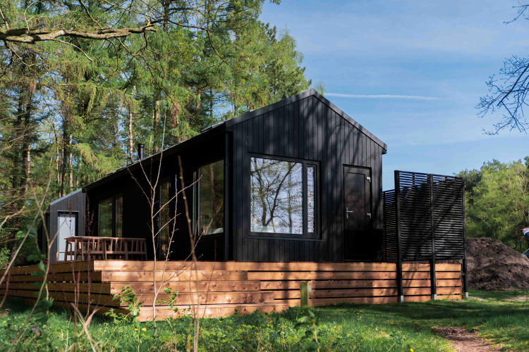 Lodge en bois noir, Koya Tiny Cabin, avec terrasse, située dans la forêt à Wilsumer Berge, Allemagne.