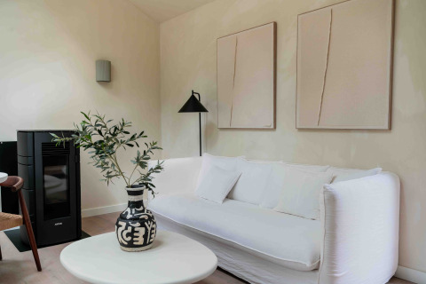 Sala moderna en Koya Tiny Cabin, Wilsumer Berge, con sofá blanco, jarrón negro y arte minimalista en la pared.