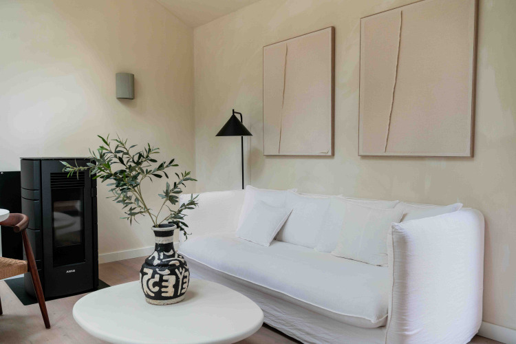 Modern living room in Koya Tiny Cabin, Wilsumer Berge, featuring white sofa, black vase, and abstract art.
