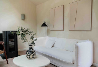 Moderne woonkamer in Koya Tiny Cabin, Wilsumer Berge, met witte zetel, zwarte vaas en abstract kunstwerk.