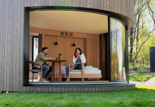 Dos personas se relajan en una moderna tiny house Lumni Pod en Wilsumer Berge, Alemania, junto a la naturaleza.