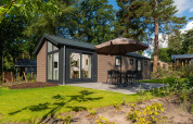 Komfortable Velthorst-Lodge mit Terrasse und Sonnenschirm im Veluwepark de Bosgraaf, Niederlande, im Grünen.