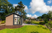 Velthorst Comfort-Lodge im Veluwepark de Bosgraaf, Niederlande, gelegen in einer grünen Gartenlandschaft.