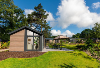 Lodge Velthorst Comfort moderno presso Veluwepark de Bosgraaf nei Paesi Bassi, circondato da alberi e giardino.