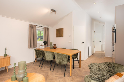 Eethoek met houten tafel en groene stoelen in een moderne lodge bij Velthorst Comfort, Veluwepark de Bosgraaf, Nederland.