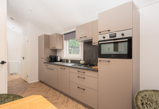Cucina moderna al Velthorst Comfort lodge nel Veluwepark de Bosgraaf, Paesi Bassi, con mobili eleganti.