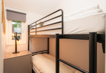 Modern bunk bed near window and table lamp in Velthorst Comfort at Veluwepark de Bosgraaf, Netherlands.