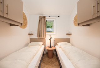 Et lyst, moderne værelse med to enkeltsenge, natbord og vindue på Velthorst Comfort, Veluwepark de Bosgraaf.