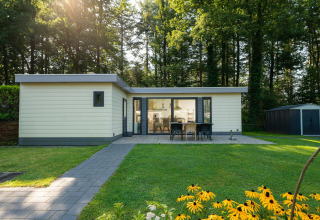 Udendørs udsigt over Comfort Chalet ved Veluwepark de Bosgraaf, Nederlandene, med terrasse og have.