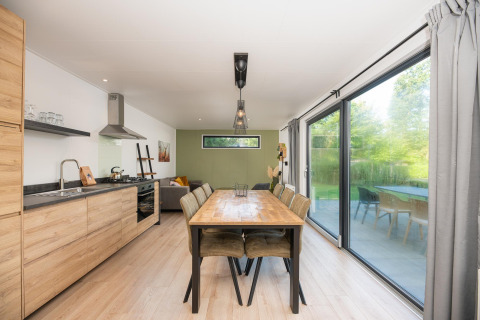 Modernes Ess- und Wohnzimmer in einem Comfort Chalet im Veluwepark de Bosgraaf, Niederlande, mit großen Fenstern.