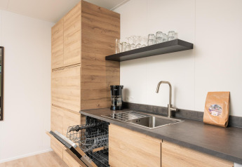 Moderne Küchenzeile im Comfort Chalet im Veluwepark de Bosgraaf, Niederlande, mit offener Spülmaschine.