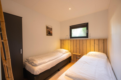 Zimmer mit zwei Einzelbetten, Fenster und Schrank im Comfort Chalet im Veluwepark de Bosgraaf, Niederlande.