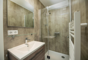 Moderne badeværelse på Comfort Chalet, Veluwepark de Bosgraaf, med bruseniche, vask og spejl.