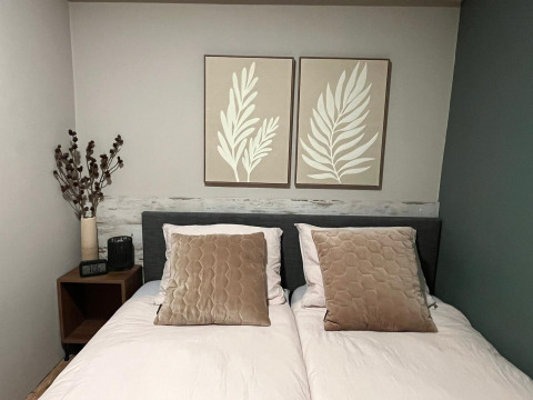 Gemütliches Schlafzimmer im Veluwe Chalet, Veluwepark de Bosgraaf, Niederlande, mit Doppelbett und Wandkunst.