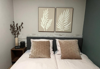 Gemütliches Schlafzimmer im Veluwe Chalet, Veluwepark de Bosgraaf, Niederlande, mit Doppelbett und Wandkunst.