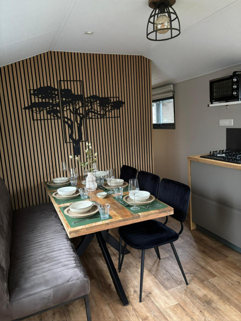 Spiseområde i Veluwe Chalet ved Veluwepark de Bosgraaf, Holland, med moderne indretning og dækket bord.