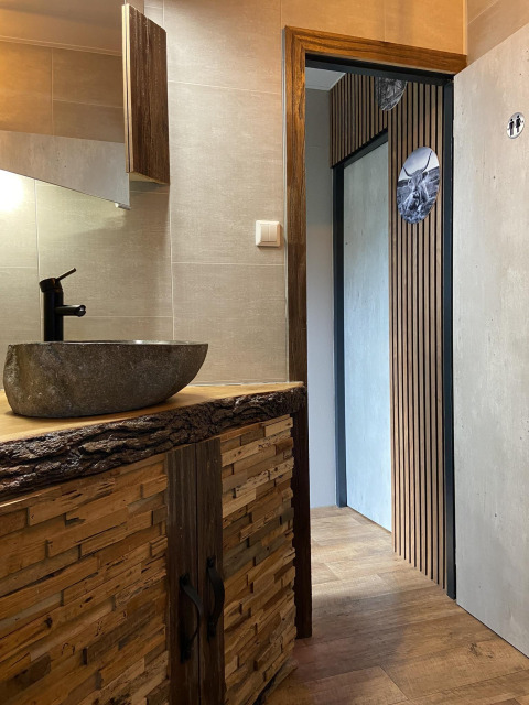 Et moderne badeværelse med naturinspireret håndvask og trædetaljer, set på Veluwe Chalet i Holland.