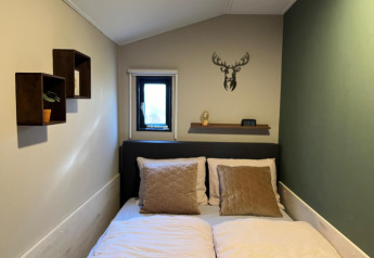 Chambre confortable au Veluwe Chalet, Veluwepark de Bosgraaf, avec lit double et décoration de cerf mural.