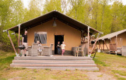 Familia disfrutando frente a una tienda safari en Wilsumer Berge, Alemania, rodeados de naturaleza verde.