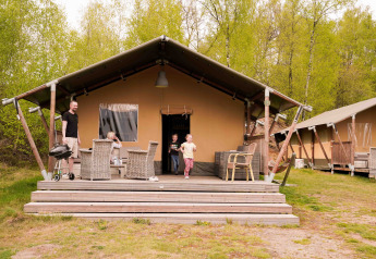 Familia disfrutando frente a una tienda safari en Wilsumer Berge, Alemania, rodeados de naturaleza verde.