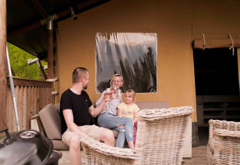 Familia relajándose frente a una tienda safari en Wilsumer Berge, Alemania, en una tarde soleada.