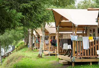 Safari-telt ved Petite Suisse i Belgien med træterrasse og tøj hængende udenfor i grønne omgivelser.