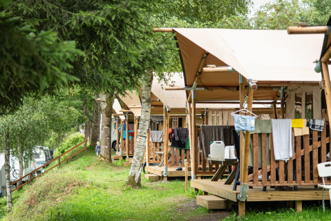 Safari-telt ved Petite Suisse i Belgien med træterrasse og tøj hængende udenfor i grønne omgivelser.