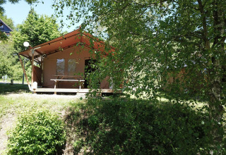 Tenda safari a Petite Suisse in Belgio, circondata da alberi e cespugli verdi in una giornata soleggiata.