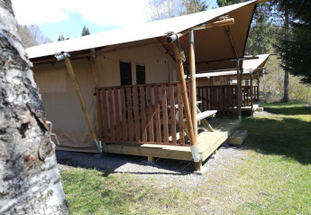Safari-telt ved Petite Suisse i Belgien med træverandaer og grønne omgivelser på campingpladsen.
