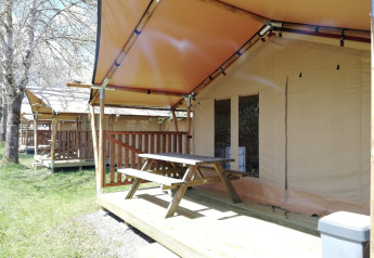 Safari-Zelte bei Petite Suisse in Belgien mit Holzterrasse und Picknicktisch an einem sonnigen Tag.