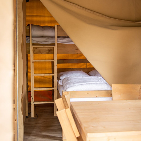Innenaufnahme eines Safarizeltes in Petite Suisse, Belgien, mit Etagenbett und Holzmöbeln.