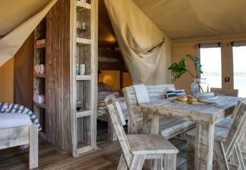 Interior view of Safari tent at Petite Suisse in Belgium featuring rustic wooden furniture and cozy decor.