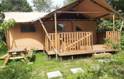 Tente safari Dreamer à Petite Suisse en Belgique, entourée de verdure avec terrasse et table de pique-nique.