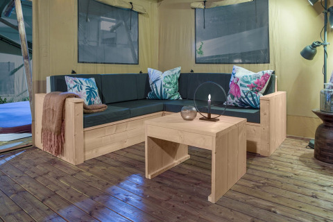 Knusse zithoek in safaritent Dreamer bij Petite Suisse, België, met stijlvolle houten meubels.