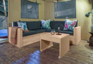 Knusse zithoek in safaritent Dreamer bij Petite Suisse, België, met stijlvolle houten meubels.