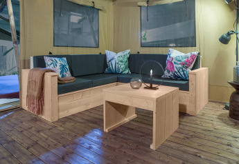 Knusse zithoek in safaritent Dreamer bij Petite Suisse, België, met stijlvolle houten meubels.