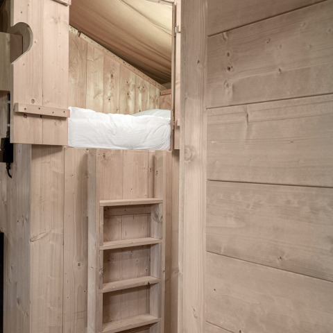 Vista interior de una acogedora litera de madera con escalera en la tienda safari Dreamer en Petite Suisse, Bélgica.