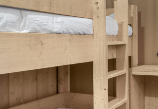 Letto a castello in legno chiaro con lenzuola bianche nella tenda safari Dreamer a Petite Suisse, Belgio.