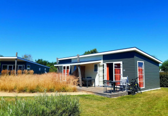Pequeña casa moderna Comfort Lodge en Kompas Camping - Westende, Bélgica, bajo un cielo azul brillante.