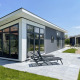 Moderne Premium Lodge ved Kompas Camping - Westende i Belgien med solstole på terrasse og blå himmel.