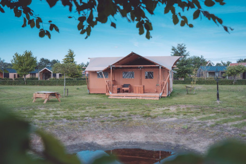Tienda safari Groupaccommodation 'de Blokhut' en Holiday park Eigen Wijze, rodeada de césped y árboles.