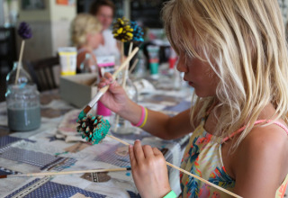 Una bambina dipinge una pigna durante un laboratorio creativo all'Holiday Park Bonte Vlucht a Utrecht, Paesi Bassi.