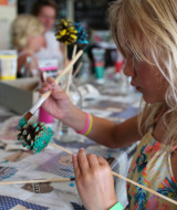 Ein Kind bemalt einen Tannenzapfen bei einer Kreativwerkstatt im Ferienpark Bonte Vlucht in Utrecht.