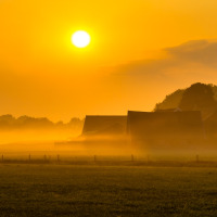 Amanecer sobre un parque vacacional con alojamientos glamping, campos tranquilos y neblina matinal.